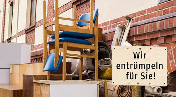 Möbel und andere zu entrümpelnde Gegenstände stehen gestapelt auf vor einer Hauswand